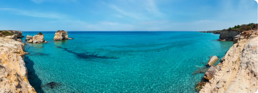 Vista panoramica di una costa con acque turchesi e scogliere, evidenziando la bellezza naturale del paesaggio marino