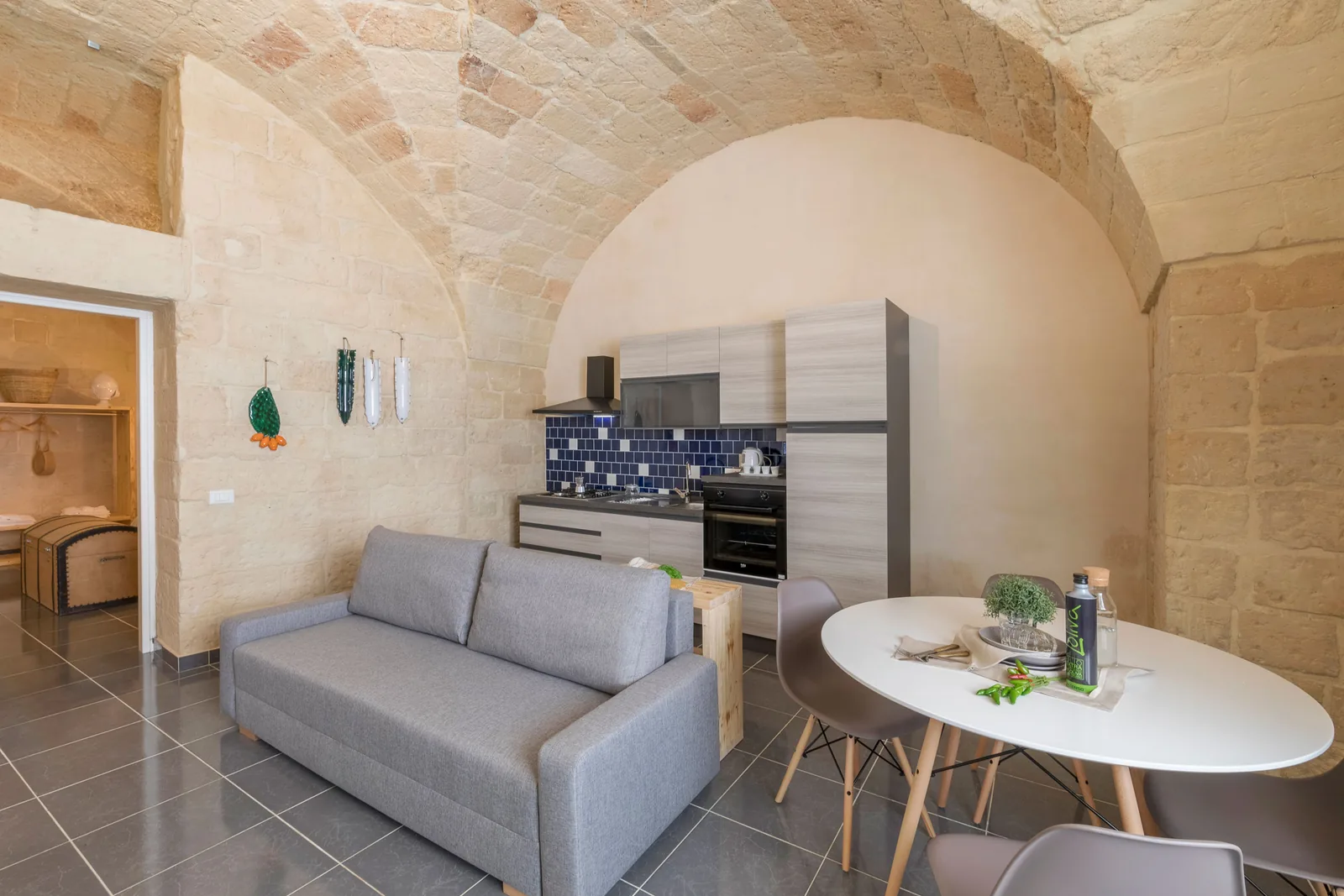 Una cucina moderna con un divano grigio e un tavolo rotondo, decorata con piatti e utensili da cucina