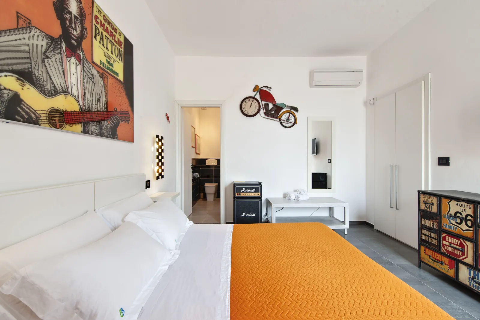 Camera da letto con un letto matrimoniale, decorazioni artistiche e un bagno visibile in fondo