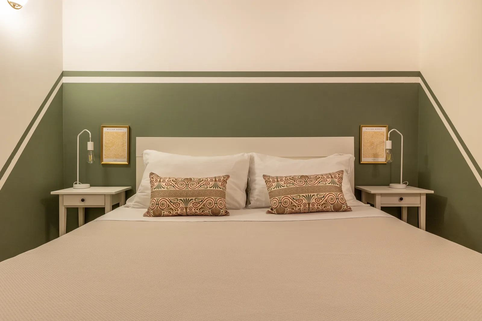 Camera da letto con un letto matrimoniale, cuscini decorativi e lampada da tavolo su un comodino