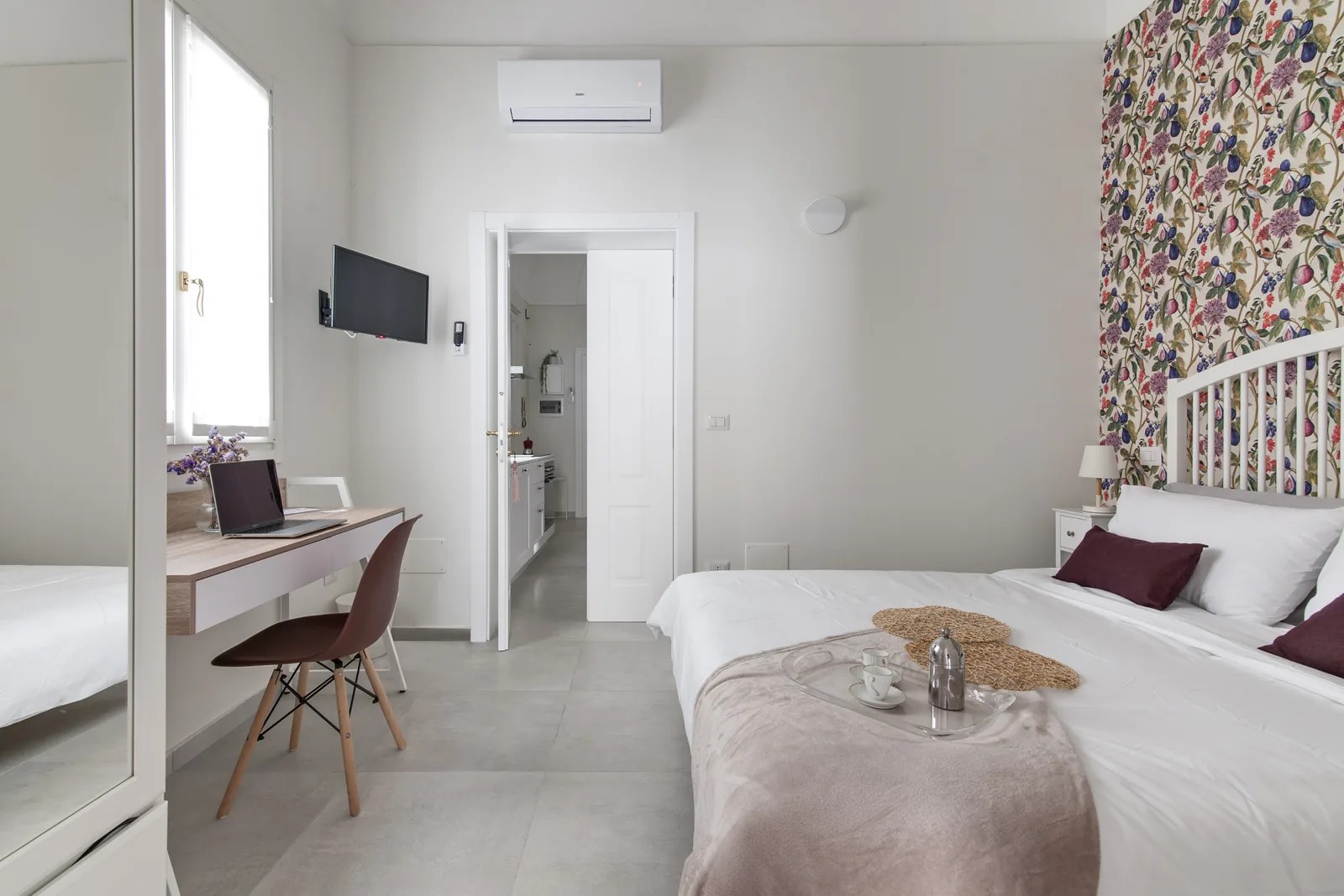 Camera da letto moderna con parete decorativa, scrivania, TV e un vassoio con tè e tazze sul letto
