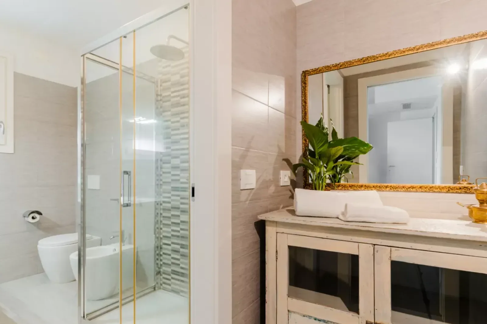 Una moderna stanza da bagno con doccia in vetro, lavabo e piante decorative su un mobile in legno