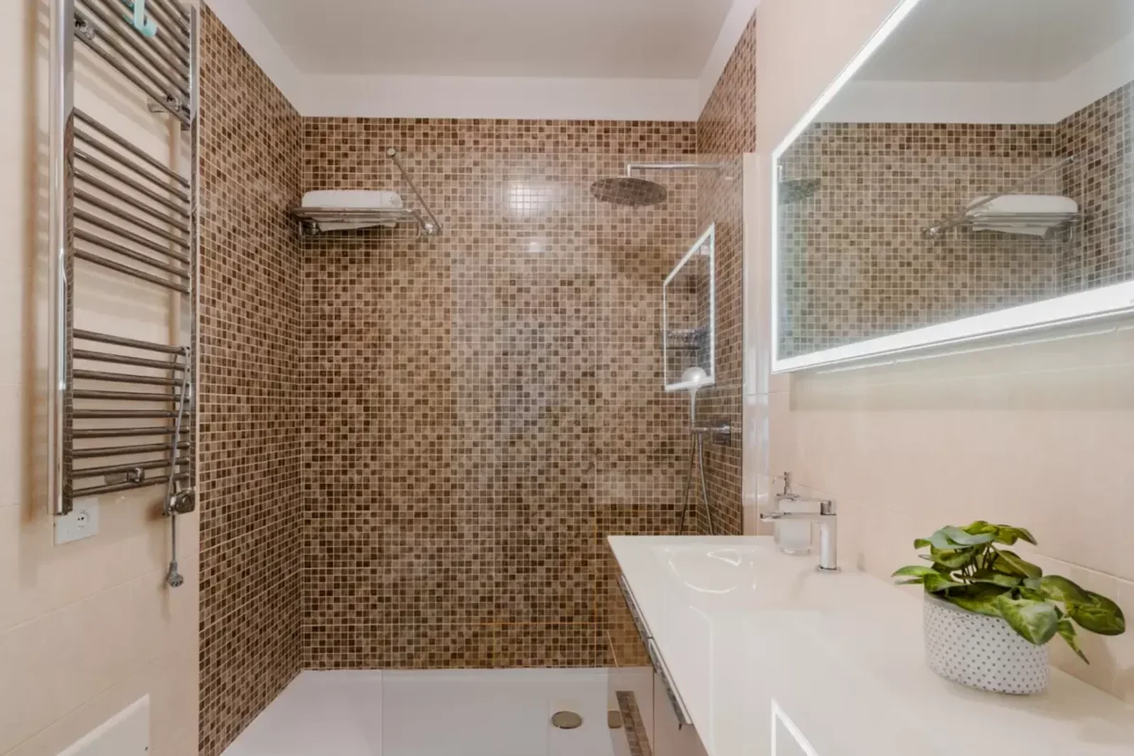 Bagno moderno con piastrelle a mosaico, doccia, lavabo e pianta in vaso